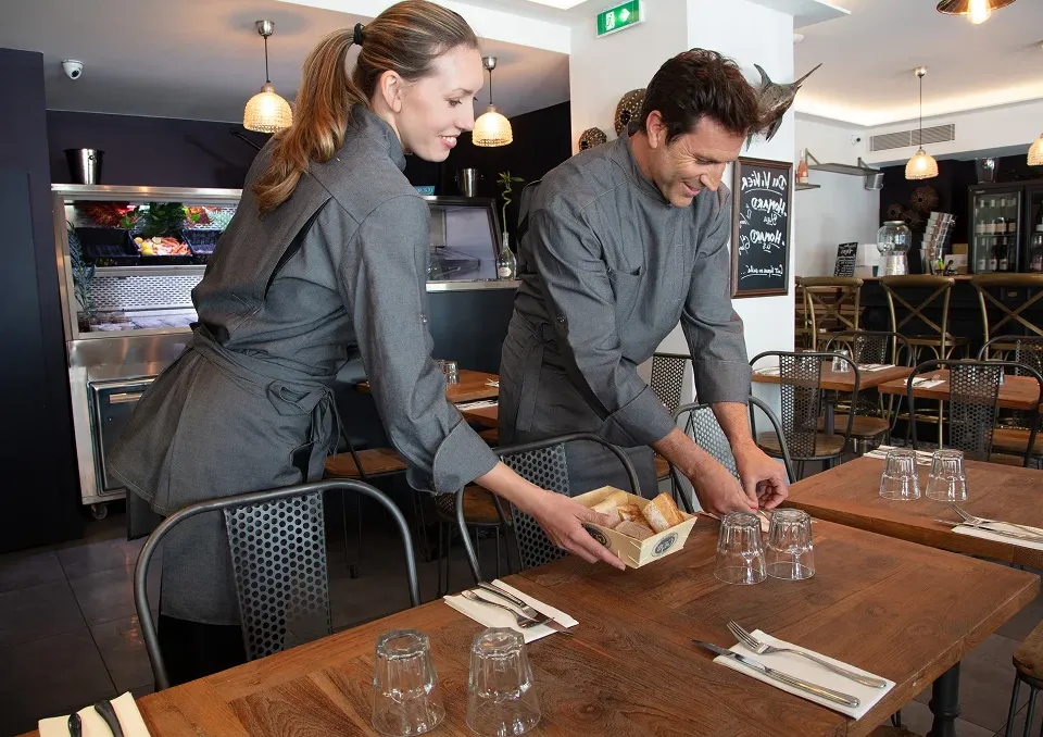 Deux personnes qui dressent une table dans un restaurant