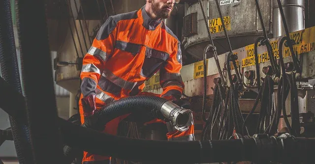 Une personne en tenue de protection manipulant un tuyau 